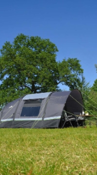 Grijze tunneltent op groene kampeerplek