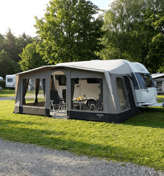 Ruime voortent met zithoek bij caravan op zonnige camping