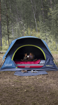 Blauwe tent met gele accenten in bosrijke omgeving