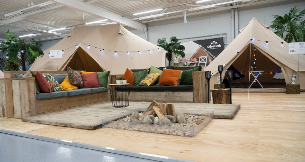 Winkel met sahara tenten Luxe beige glampingtenten met kleurrijke kussens op houten terras, decoratieve vuurplaats en feestverlichting in showroom opstelling