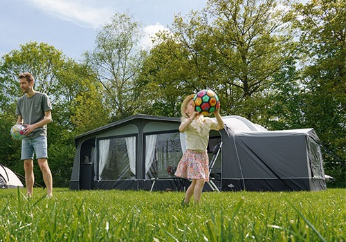 voortent met aanbouw en gezin ervoor aan het spelen